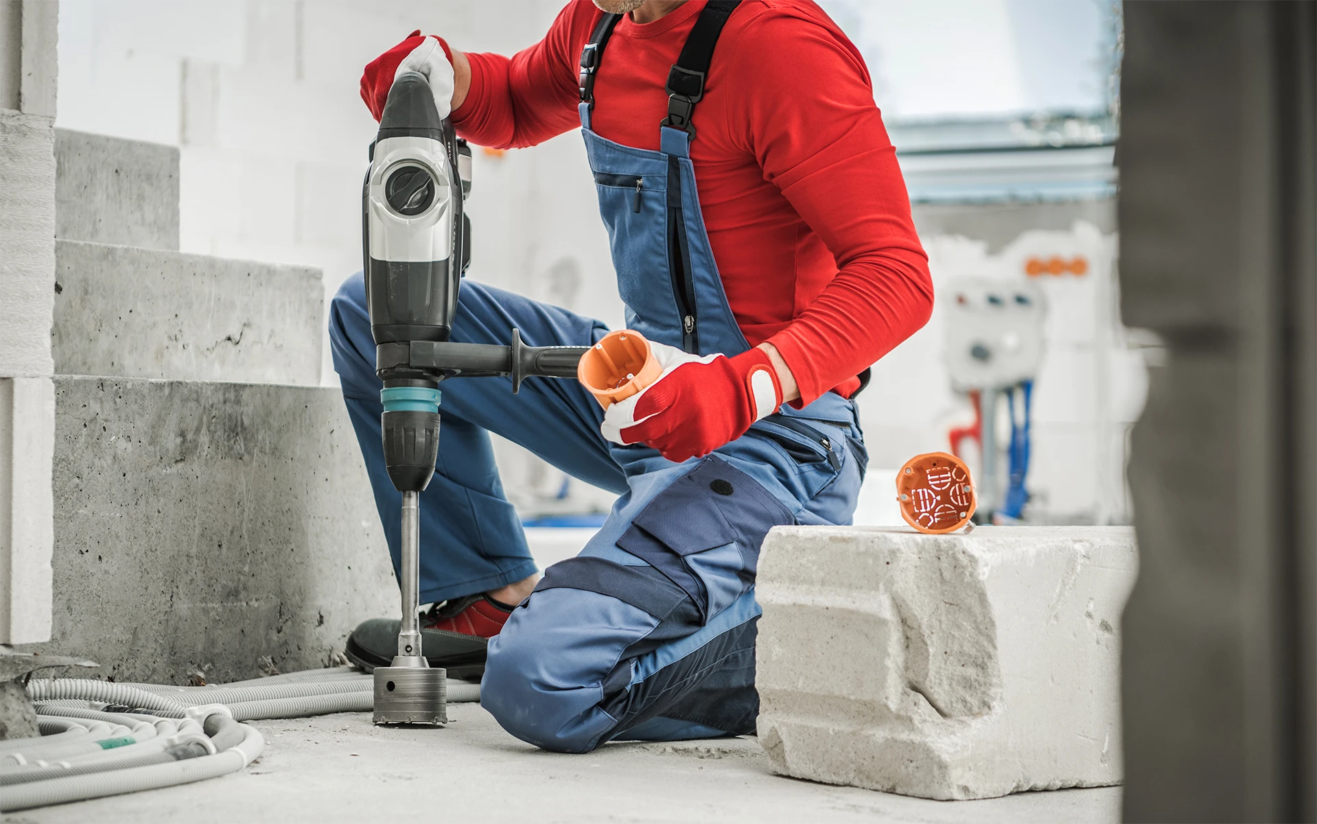 Handwerker führt Kernbohrung in Mauerwerk durch und bereitet Elektroinstallationen im Rohbau vor.